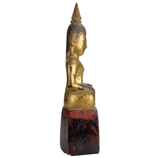 Phra Chao Mai Buddha auf einem hohen Holzsockel mit alter Tempelpatina und Vergoldungsspuren