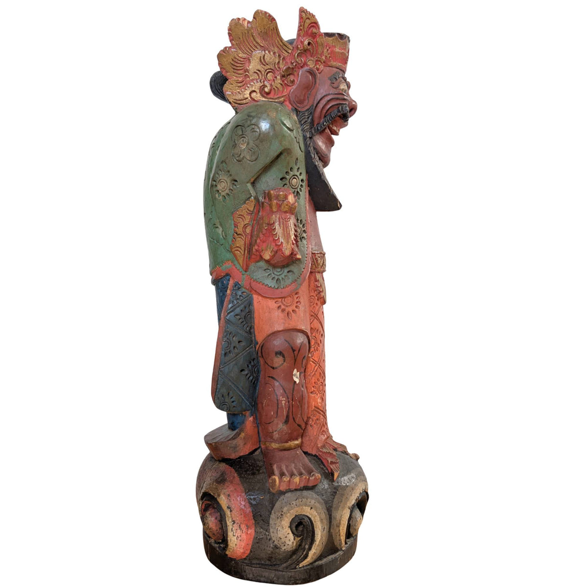 Side view of the wooden Balinese guardian figure on a stylized pedestal