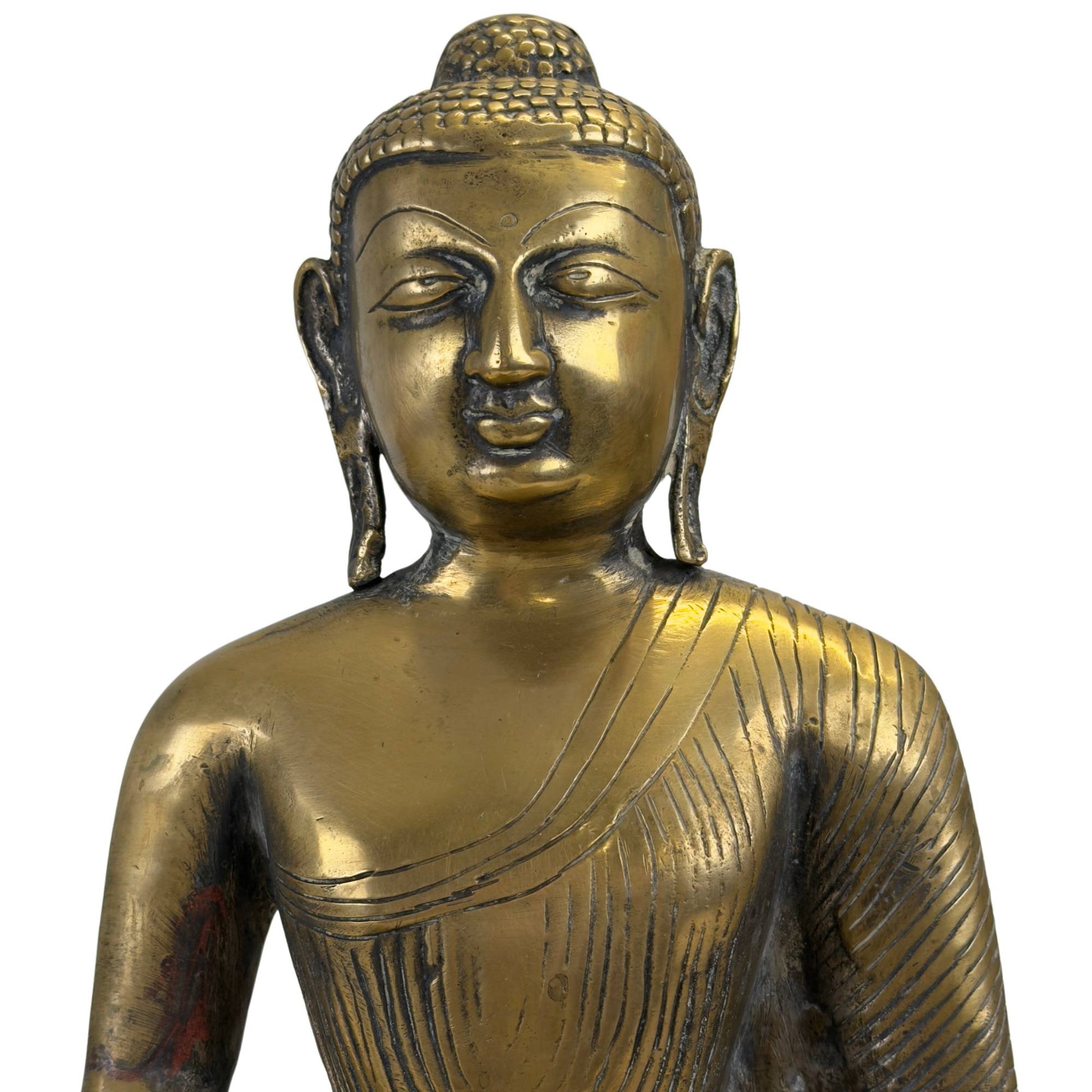 Nahaufnahme des heiteren Gesichts des bronzenen Buddhas mit dem charakteristischen Urna-Punkt und den zarten Haarspiralen