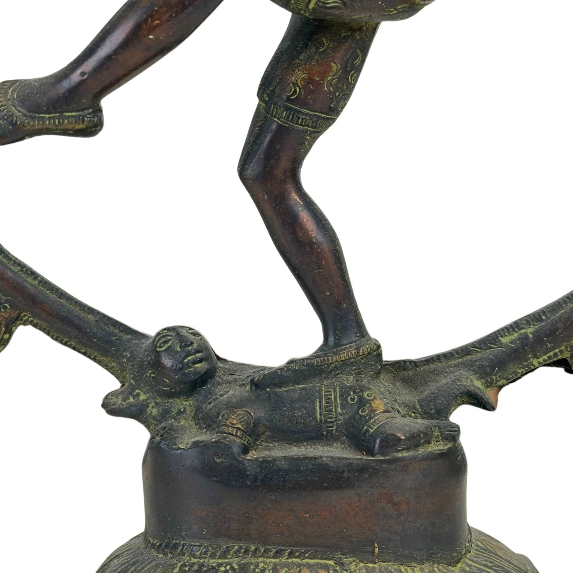 Nahaufnahme des Zwerges Apasmara zu Füßen von Shiva Nataraja auf dem bronzenen Lotussockel