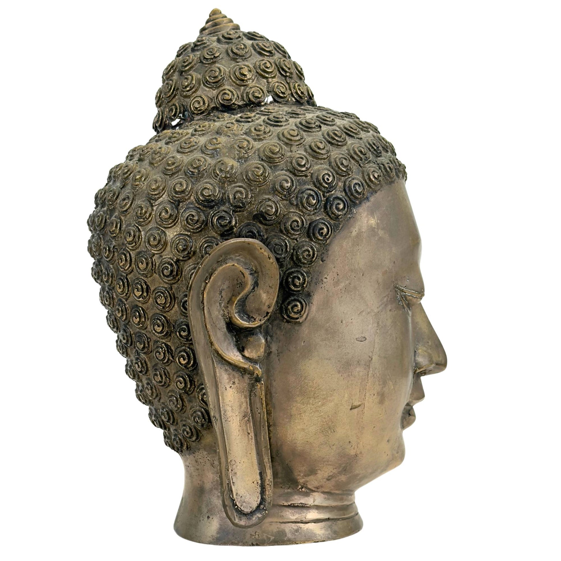 Dreiviertelansicht von links des antiken Buddha-Kopfes aus Messingbronze, die die verlängerten Ohrläppchen und das fließende Gesichtsprofil zeigt.