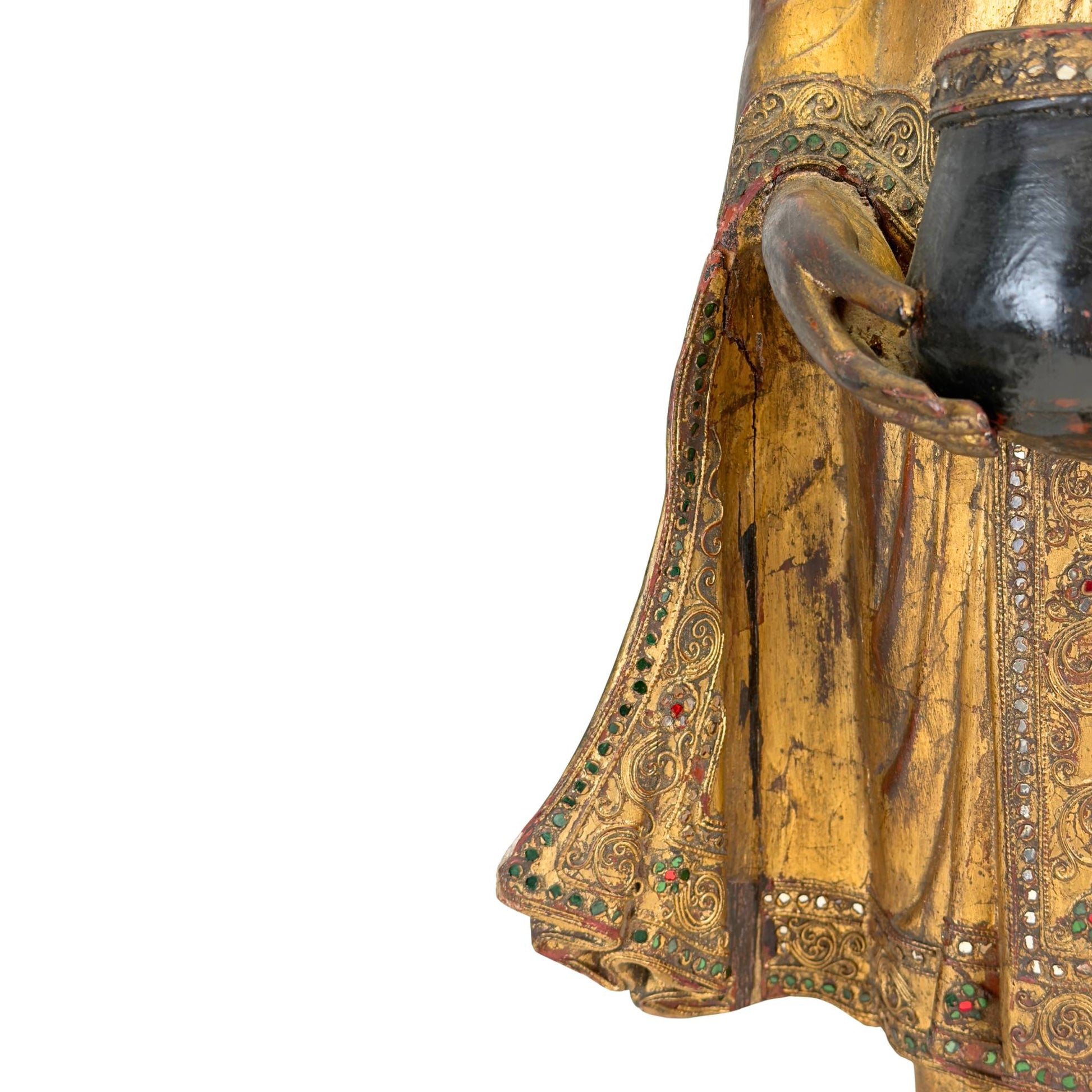 Detailaufnahme der linken Hand und des Gewandes des alten burmesischen Buddha, mit Fokus auf die filigranen Hmankazi-Glasintarsien und die historische Lackierung.