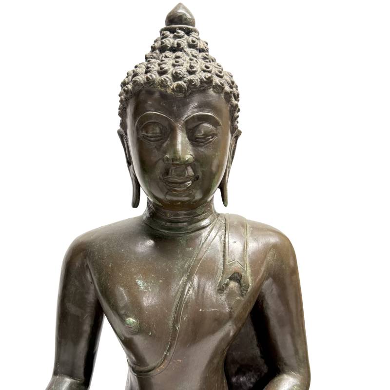 Nahaufnahme des heiteren Gesichts des Shakyamuni Buddha mit gesenktem Blick, verlängerten Ohrläppchen und einem ausgeprägten meditativen Ausdruck.