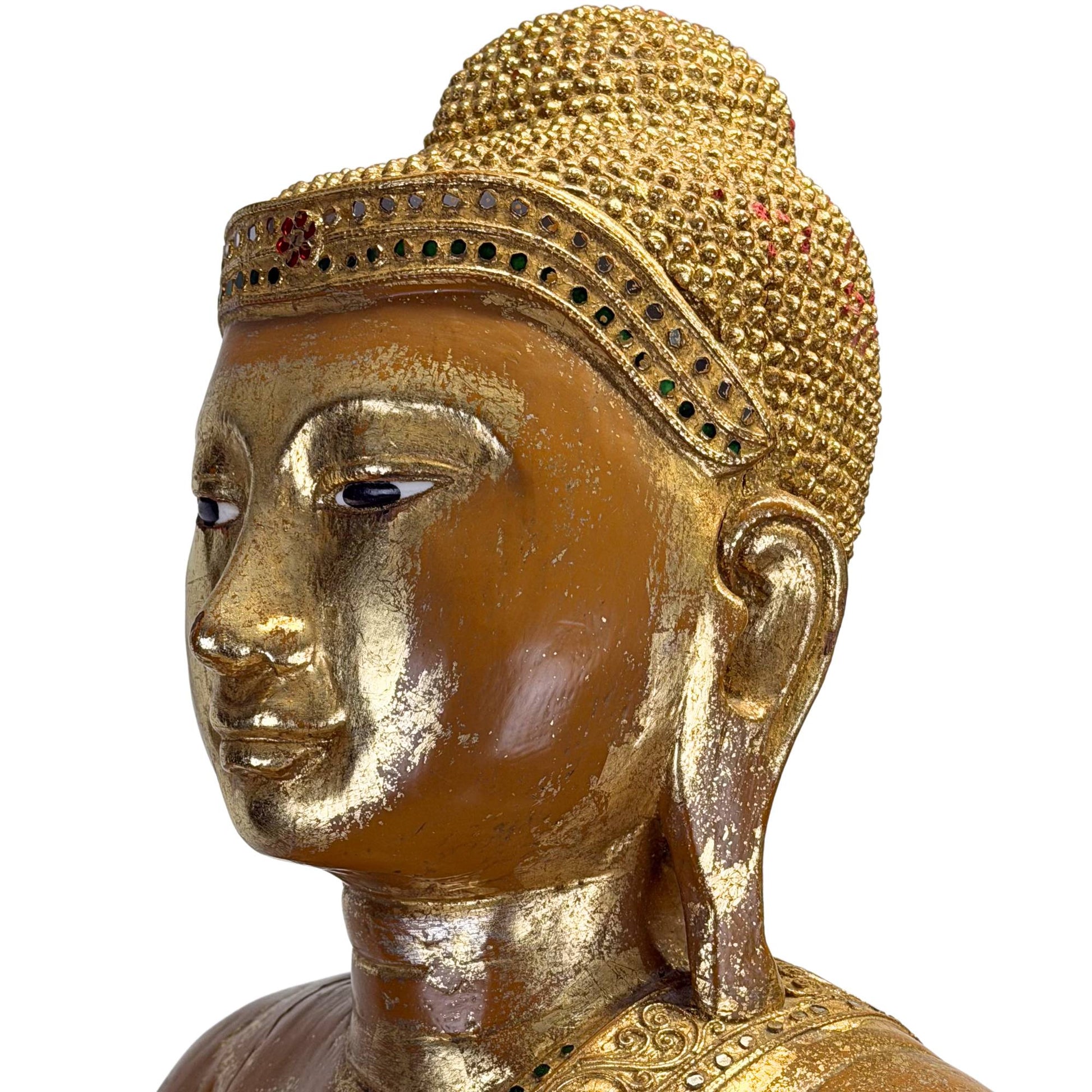 Gesicht eines antiken burmesischen Buddhas mit eingelegten Augen, einem goldenen Stirnband und einem ruhigen, meditativen Ausdruck.