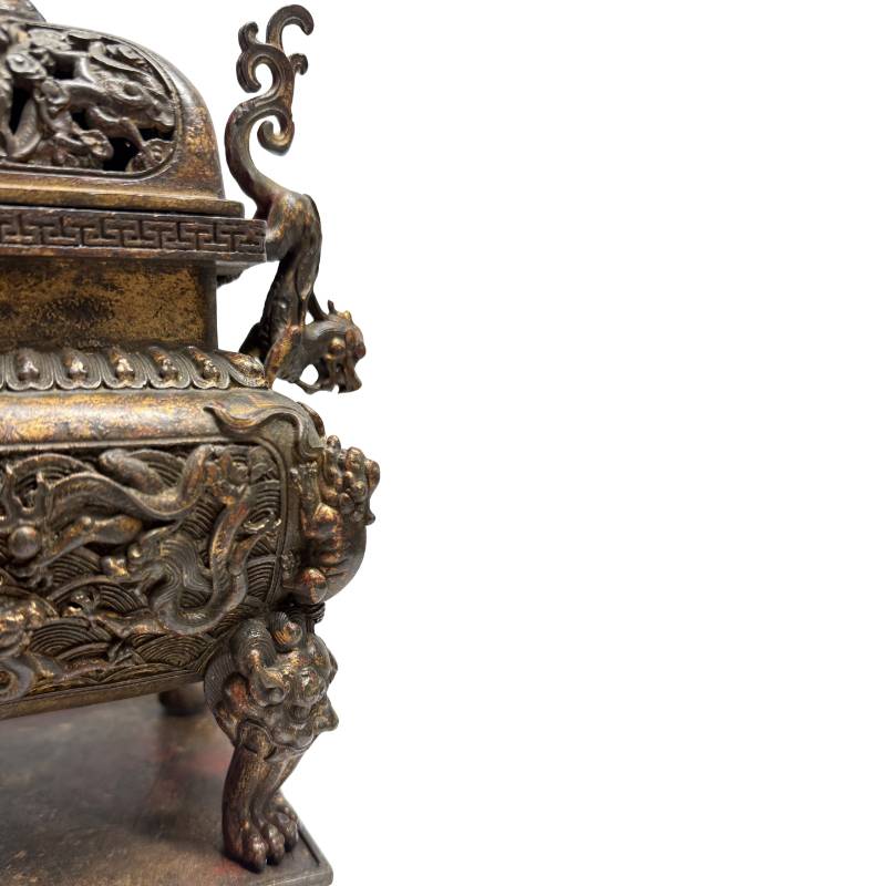 Nahaufnahme der rechten Seite mit dem gegossenen Löwenkopf auf der Pfote und der geschichteten, dunklen Patina auf der Bronzewand.