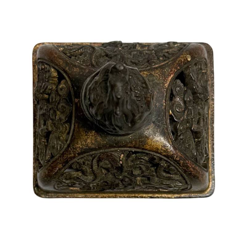 Draufsicht auf den losen, rechteckigen Bronzedeckel mit fein durchbrochenem Wolkenrelief und einem zentralen flammenden Knauf.
