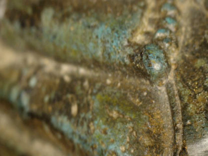 Mikroskopdetail von Gewand und Brust mit blaugrüner Kupferpatina und natürlicher Abnutzung