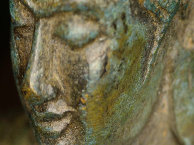 Mikroskopdetail des Gesichts mit Patina und winzigen Resten einer früheren Vergoldung