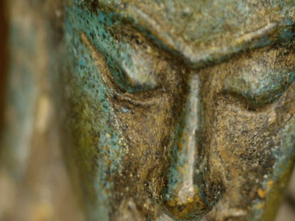 Mikroskopdetail von Augen, Nase und alter Patina im Gesicht des antiken thailändischen Buddhas
