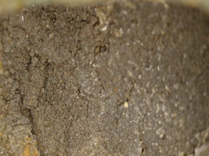 Mikroskopdetail der körnigen alten Gusskernstruktur und rauen bronzenen Innenwand