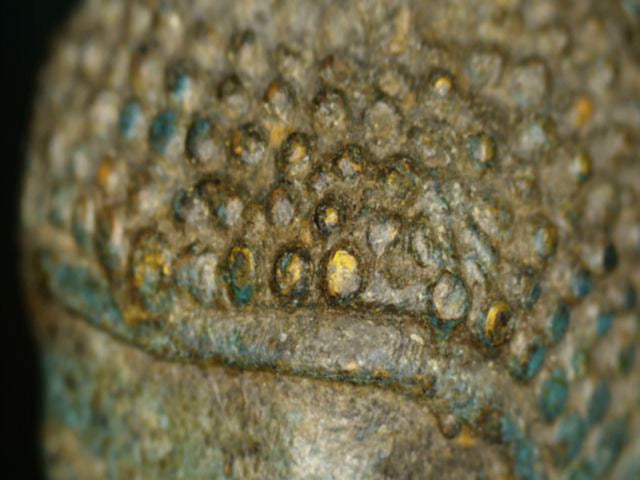 Mikroskopdetail der Haarkringel mit verstreuten goldfarbenen Resten und alter Patina