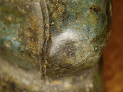 Mikroskopdetail der abgeriebenen Knieoberfläche mit umgebender alter Patina am Thai-Buddha