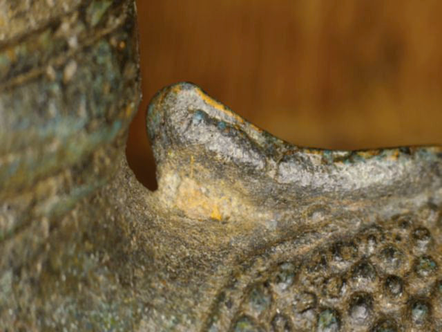 Mikroskopdetail der flammenförmigen Ushnisha mit dünnen goldfarbenen Resten am antiken Thai-Buddha