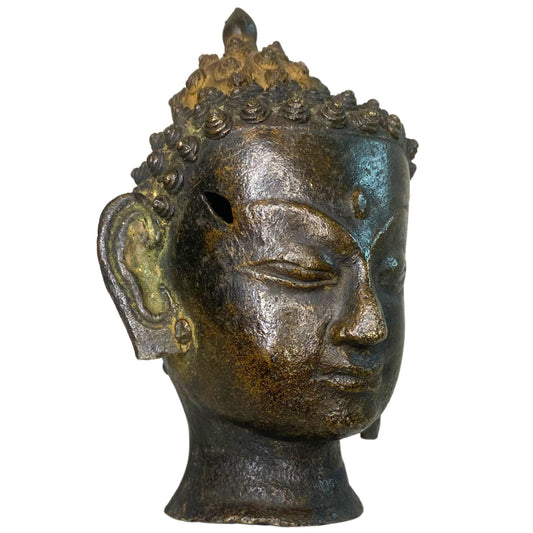 Rechtsprofil des bronzenen Buddha-Kopfes mit einem sichtbaren historischen Loch an der Seite.