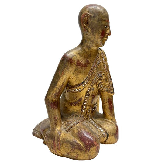 Nahaufnahme von authentischem Blattgold und rotem Lack auf einer antiken Holzstatue.