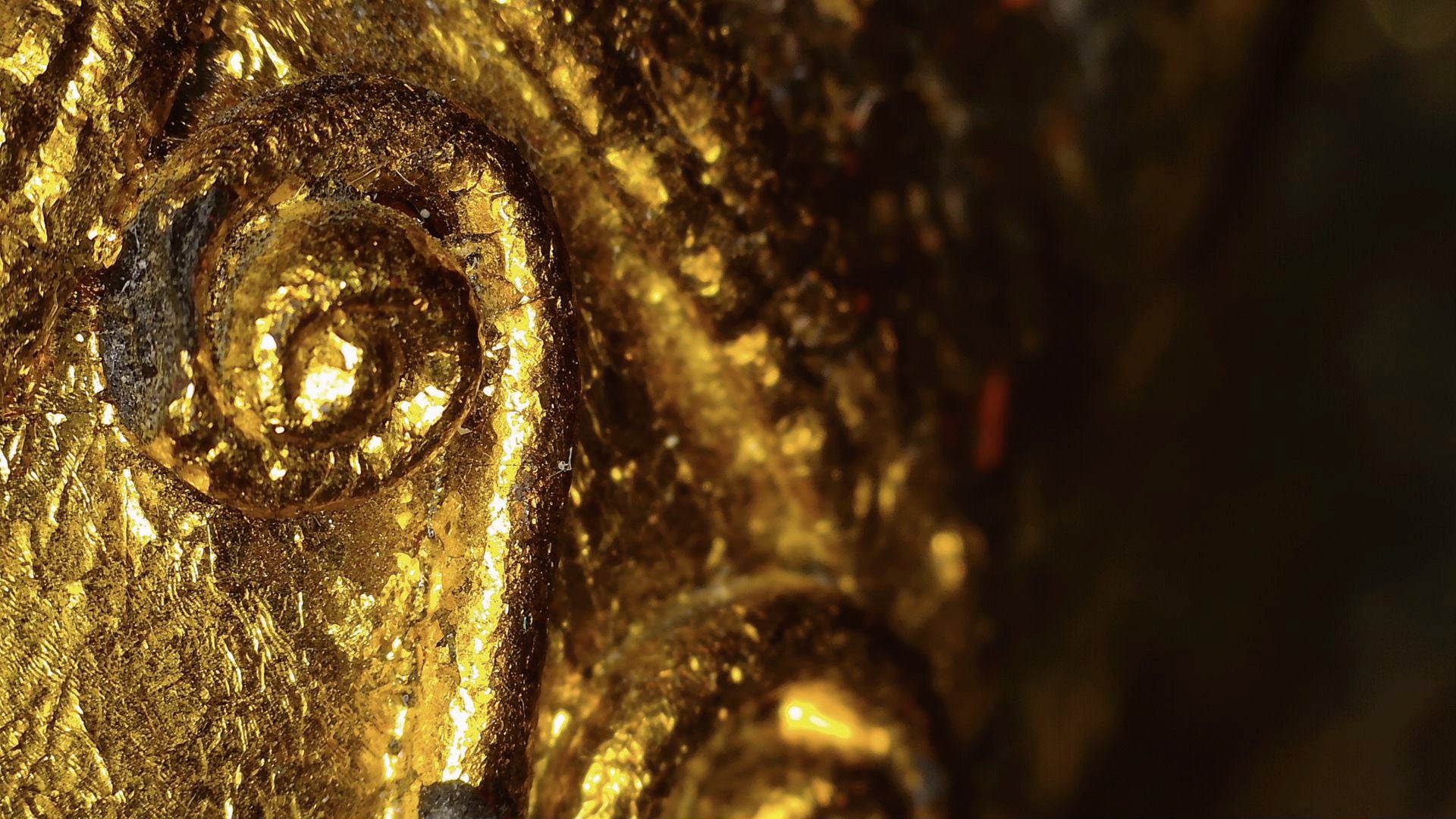 Mikroskopdetail von Blattgold und Reliefdekor an der birmanischen Skulptur