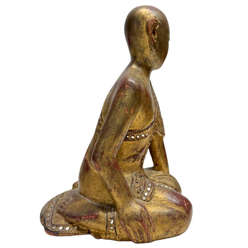 Seitenansicht eines knienden buddhistischen Mönchs in andächtiger Haltung.
