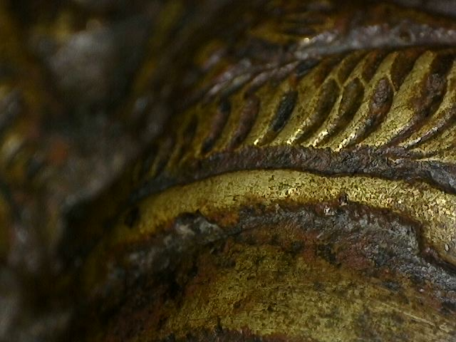 Mikroskopische Detailaufnahme von rituellen Gebrauchsspuren an einer Brahma-Statue aus Bronze.