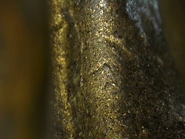 Mikroskopische Detailaufnahme der Oxidation mit Cuprit und Malachit an einer Buddha-Statue aus Bronze