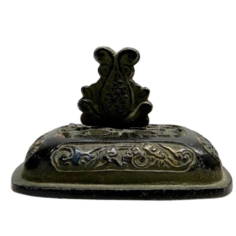 Nahaufnahme des losen Bronzedeckels mit Wolkenrelief, Goldspuren und einem zentralen Knauf in Form eines Lotusjuwels.