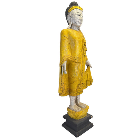 Schräge Frontalansicht der Buddha-Statue, die die detaillierten Reliefapplikationen an den Rändern des Gewandes zeigt.