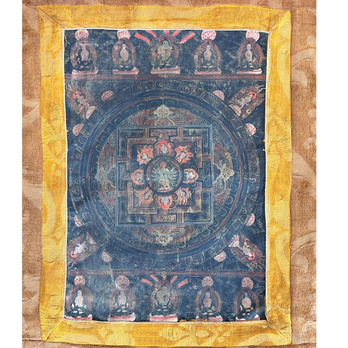 Bildfeld des Mandala-Thangkas innerhalb der gelben Seidenbordüre, oben und unten je eine Reihe sitzender Figuren