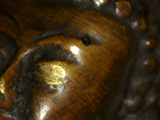 Mikroskopische Nahaufnahme der alten Feuervergoldung einer Bronzebuddhafigur mit Dhyana Mudra