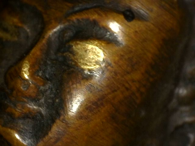 Mikroskopische Detailaufnahme von Vergoldungsresten auf einer antiken Bronze-Buddha-Figur mit Dhyana Mudra
