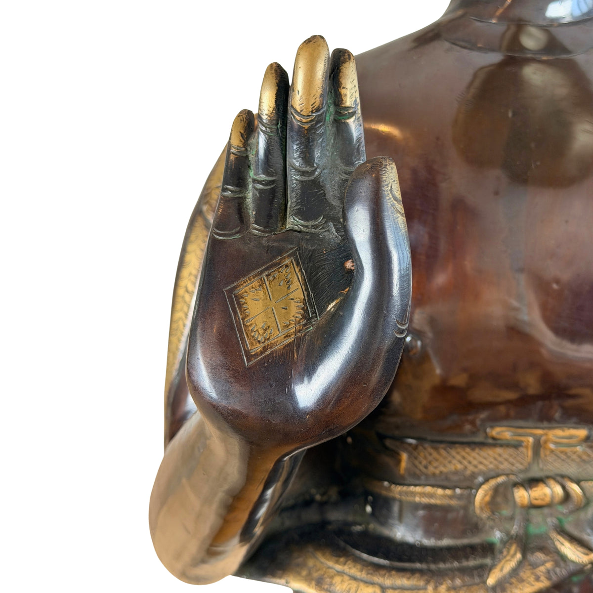 Erhobene rechte Hand in Abhaya-Mudra mit vergoldetem Handflächenzeichen, darunter der Gürtel