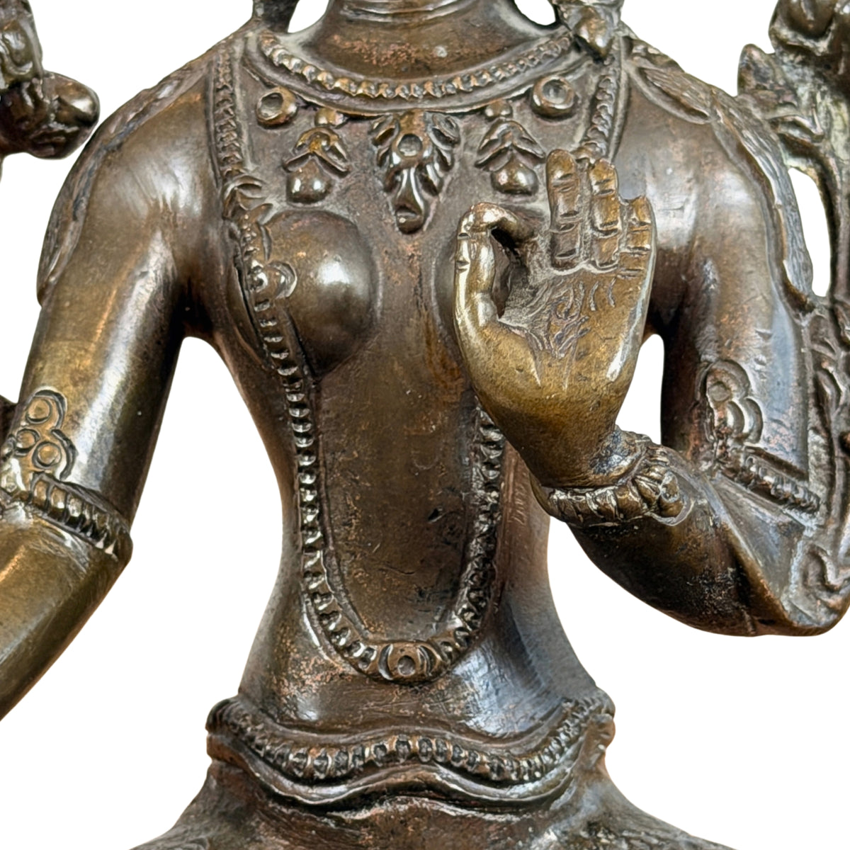 Opgeheven linkerhand in vitarka mudra voor de borst, met halssieraden, detail