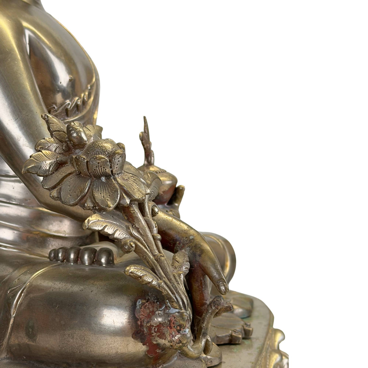 Detail der reich ausgearbeiteten Utpala‑Lotus‑ und Arzneipflanze eines antiken Newar Bhaisajyaguru aus versilberter Bronze, mit originalen rituellen Gebrauchsspuren und natürlicher Patina.