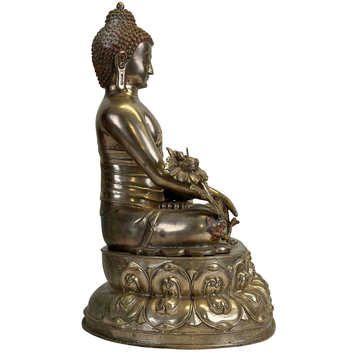 Linke Seitenansicht einer antiken Newar Bhaisajyaguru aus vergoldetem Bronze auf einem reich verzierten doppelten Lotus‑Thron mit Heilpflanze und natürlicher Patina.