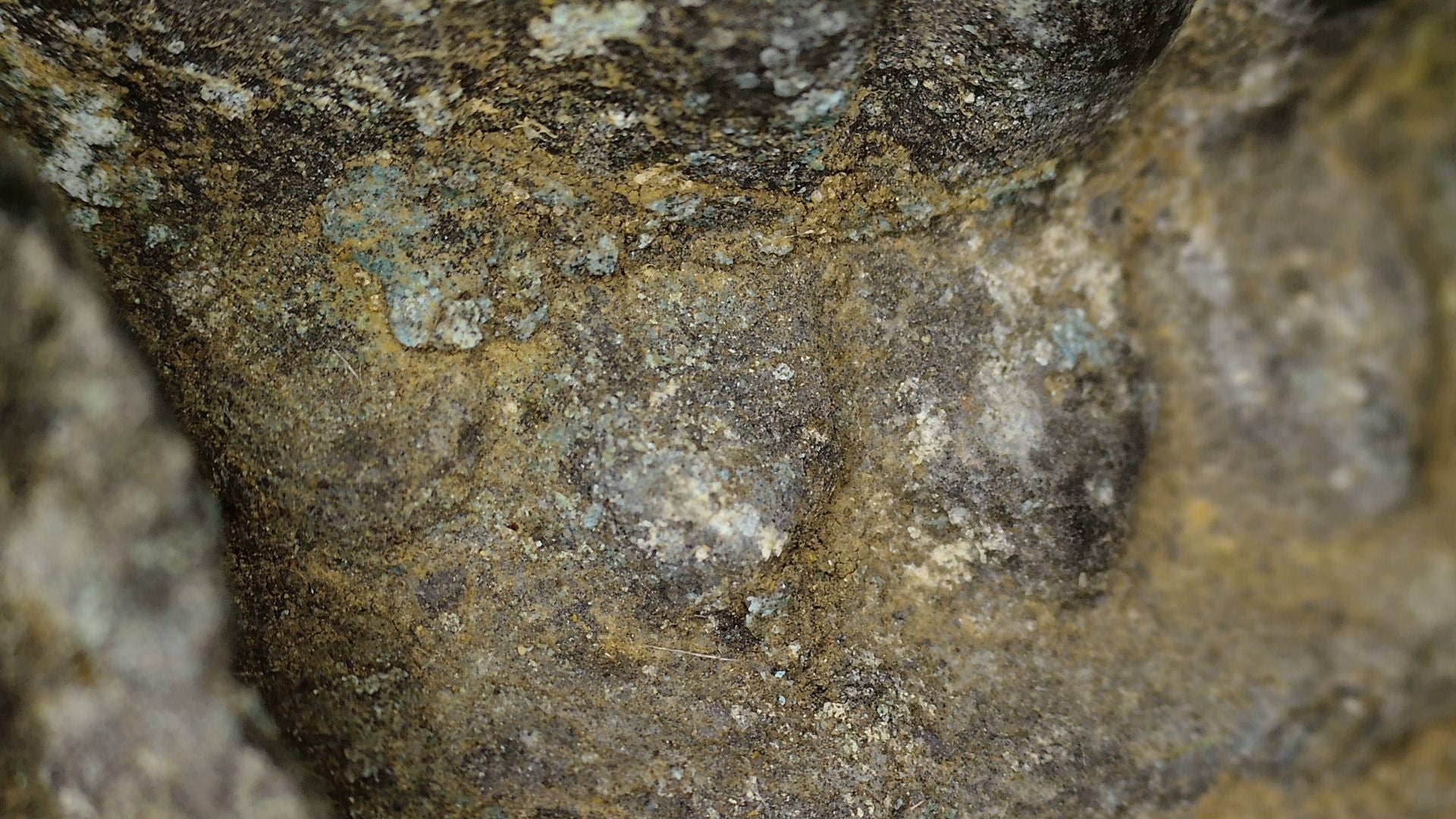 SKU 745 – Makroaufnahme mineralischer und erdiger Ablagerungen auf der Bronze-Votivstupa