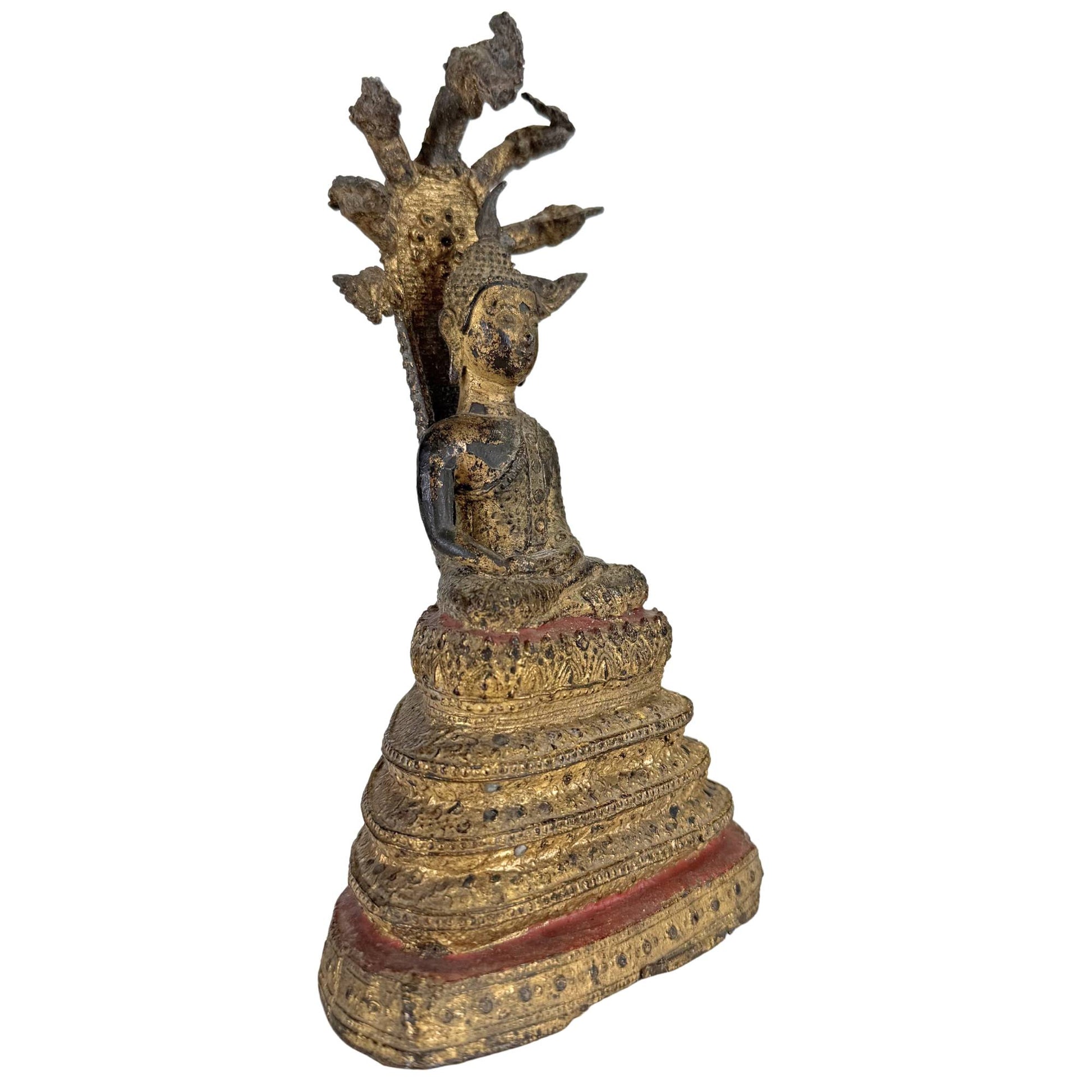 Seitenansicht eines antiken thailändischen Naga-Buddha mit vergoldeter Oberfläche und mehrköpfiger Schlange