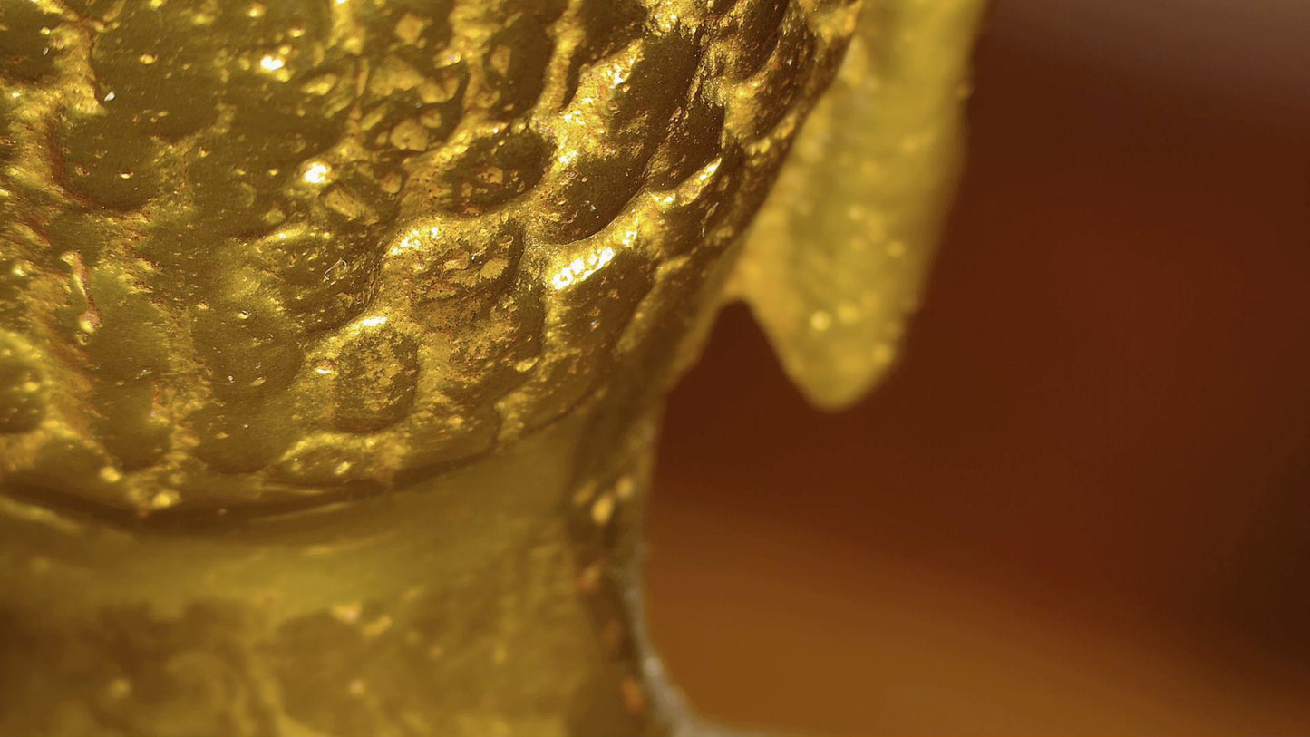 Mikroskopdetail der historischen Patina auf dem Hinterkopf einer antiken tibetischen Buddha‑Statue