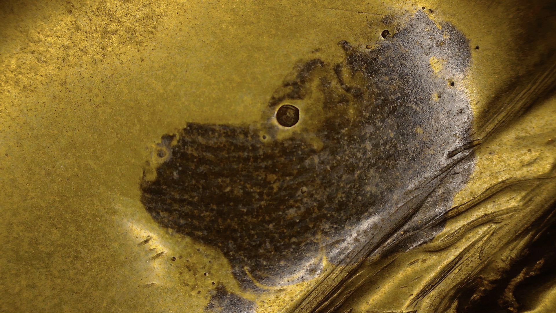 Mikroskop-Detail der braunen Patina-Oberfläche auf einem antiken tibetischen bronzenen Buddha