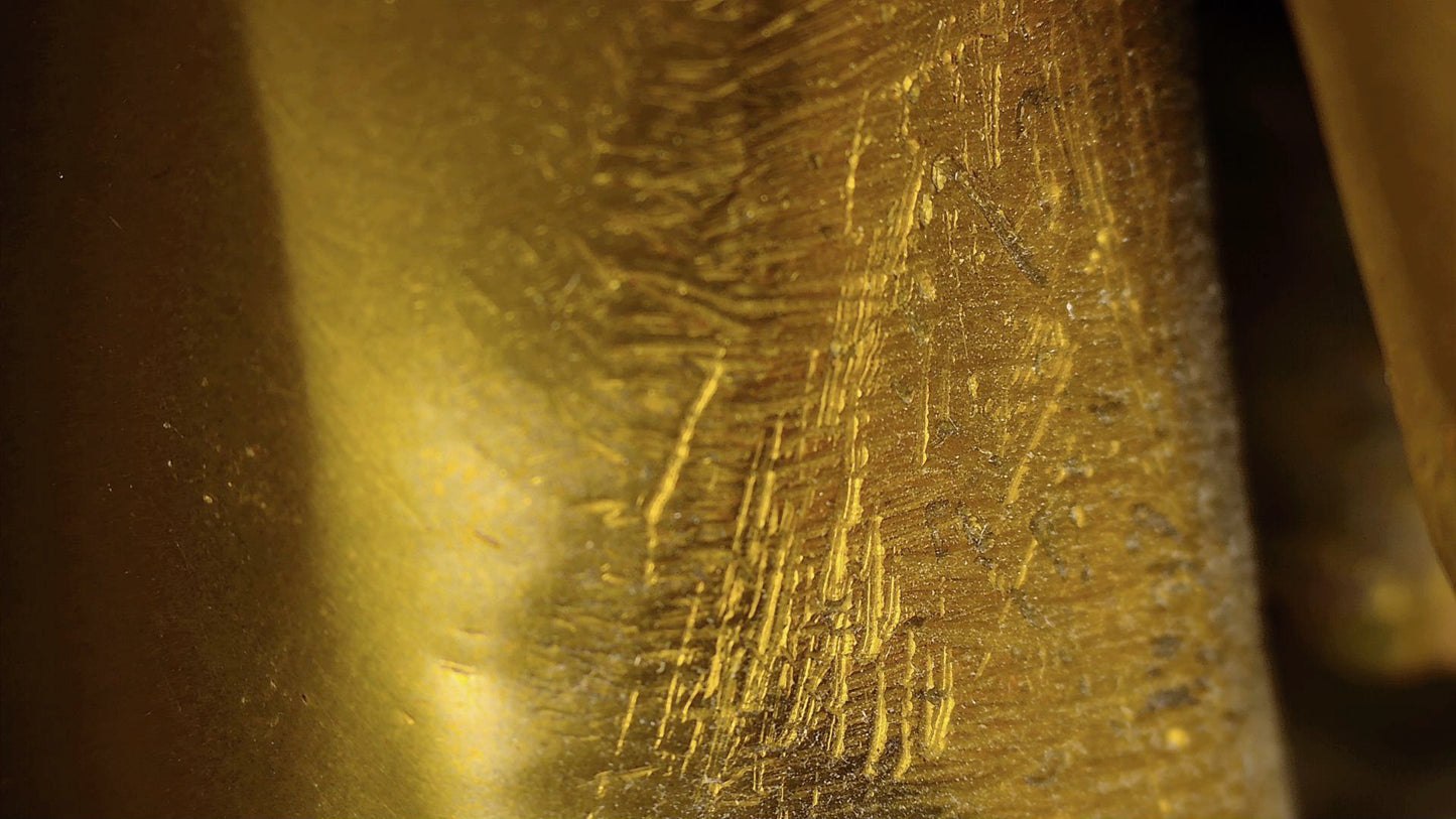 Mikroskopisches Detail von alten Kratzern und manuellen Bearbeitungsspuren an einer antiken tibetischen Buddha-Statue