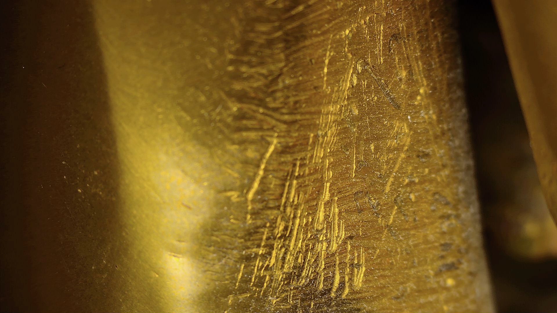 Mikroskopisches Detail von alten Kratzern und manuellen Bearbeitungsspuren an einer antiken tibetischen Buddha-Statue