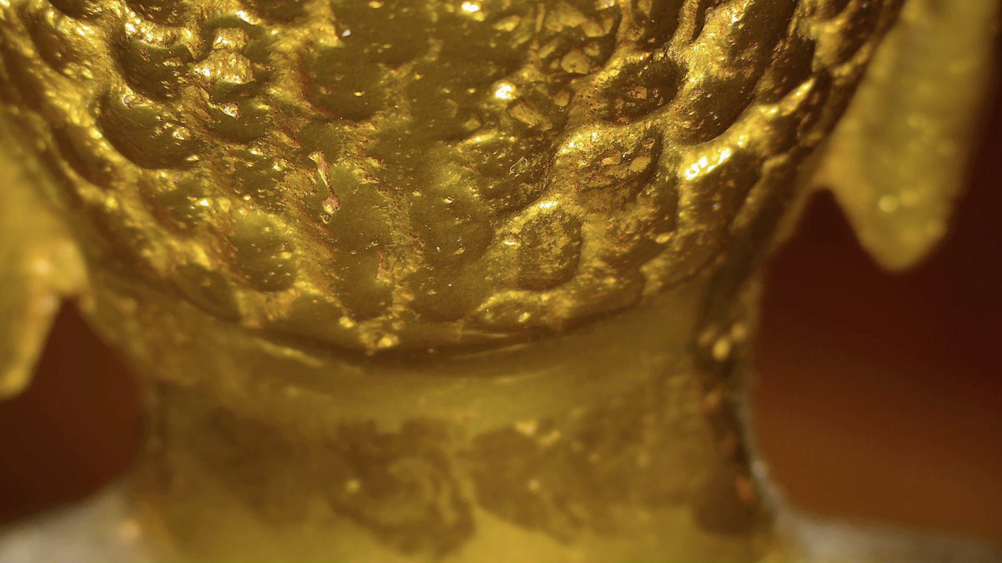Mikroskopisches Detail der alten Vergoldung und geschichteter Patina auf einem antiken tibetischen Buddha
