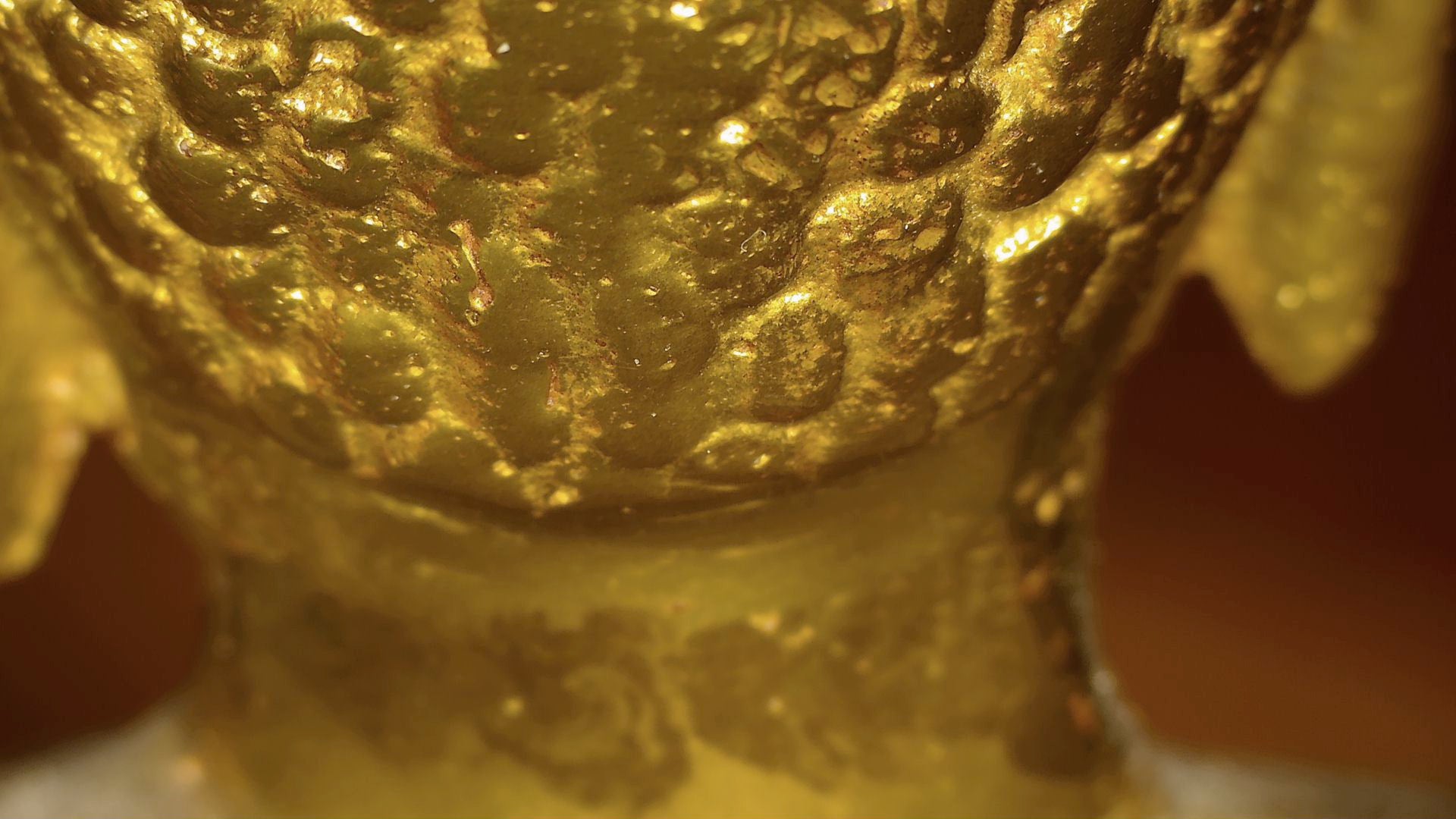 Mikroskopisches Detail der alten Vergoldung und geschichteter Patina auf einem antiken tibetischen Buddha