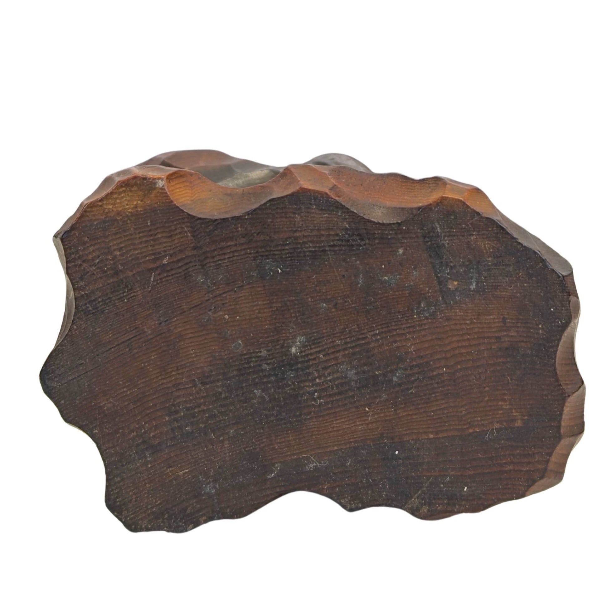 Direkte Ansicht von unten auf den massiven Holzsockel, die den flachen Querschnitt des Hinoki-Baumstamms mit dunkler, organischer Lasur zeigt.